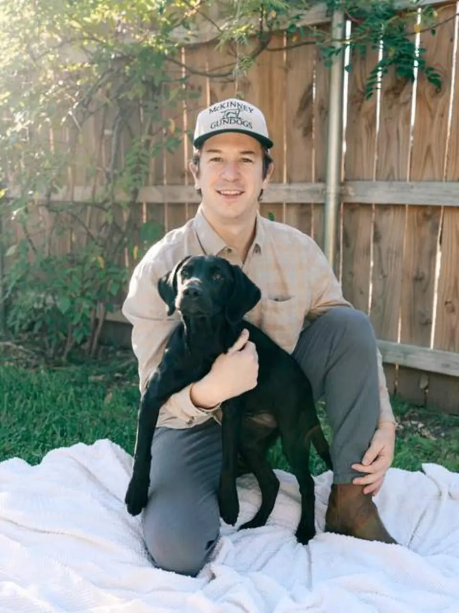 Cole McKinney holding a young black Labrador puppy